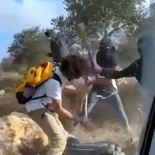 This Oct. 19, 2025, image taken from video shows what appear to be masked settlers beating activists and Palestinian farmers in Turmus Ayya, West Bank. (AP Photo)