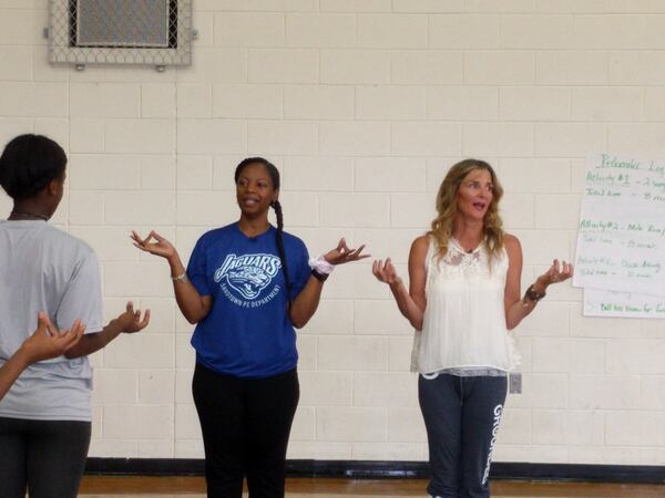 May 18, Atlanta: Cheryl Crawford (right), of Grounded Kids Yoga, leads Sandtown Middle School students in yoga with P.E. teacher Tracy Baker (in blue shirt), a former science teacher who will be teaching yoga full-time at the school in the fall after earning her yoga teaching credential from Crawford. This session at the Fulton County school's gym was a practice run.