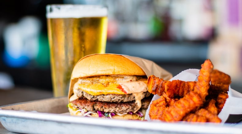 The meat-substitute Impossible Burger, Dixie Style, with sweet potato fries and a beer at Grindhouse Kiiller Burgers on Memorial Drive. Dixie Style means it comes with pimento cheese, fried green tomato, Carolina coleslaw, and chipotle ranch. CONTRIBUTED BY HENRI HOLLIS
