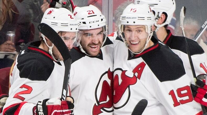 New Jersey Devils' Kyle Palmieri (21) celebrates with teammates John Moore (2) and Travis Zajac (19) after scoring against the Montreal Canadiens during the third period of an NHL hockey game, in Montreal, on Saturday, Nov. 28, 2015. (Graham Hughes/The Canadian Press via AP) MANDATORY CREDIT
