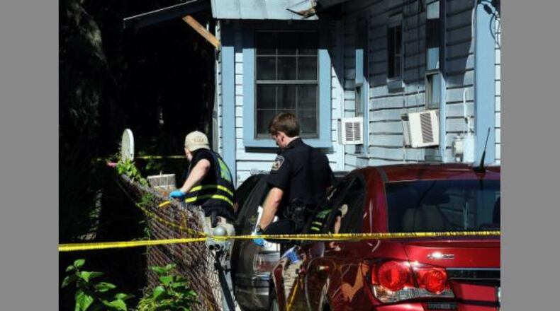 A GBI agent (left) and a Brunswick police officer search a home where a couple and their adult grandson died of gunshot wounds. (Credit: Florida Times-Union)