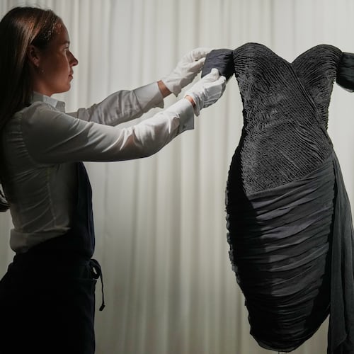 A dress worn by the late Princess Diana and known as the ''Revenge Dress'', designed by Christina Stambolian, is unveiled by staff at Sotheby’s auction house in London, Friday, Sept. 18, 2026, ahead of its Dec. 9 auction in New York, where it is estimated to sell for US$150,000-300,000. (AP Photo/Alastair Grant)