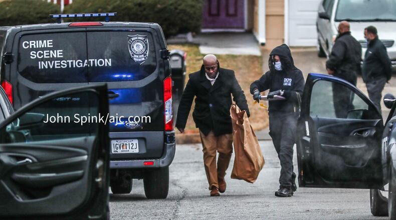 DeKalb County homicide detectives and crime scene investigators collect evidence Thursday morning outside a home on Deep Shoals Circle where a man's body was found shot multiple times.