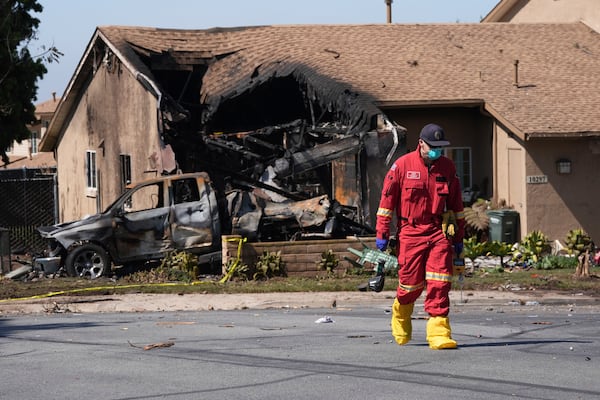 Authorities work the scene where a small plane crashed into a San Diego neighborhood, setting several homes on fire and forcing evacuations along several blocks early Thursday, May 22, 2025. (AP Photo/Gregory Bull)