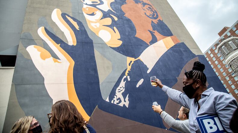 People raise a glass of champagne to the John Lewis mural after the election was called for Joe Biden Saturday, November 7, 2020. STEVE SCHAEFER / SPECIAL TO THE AJC