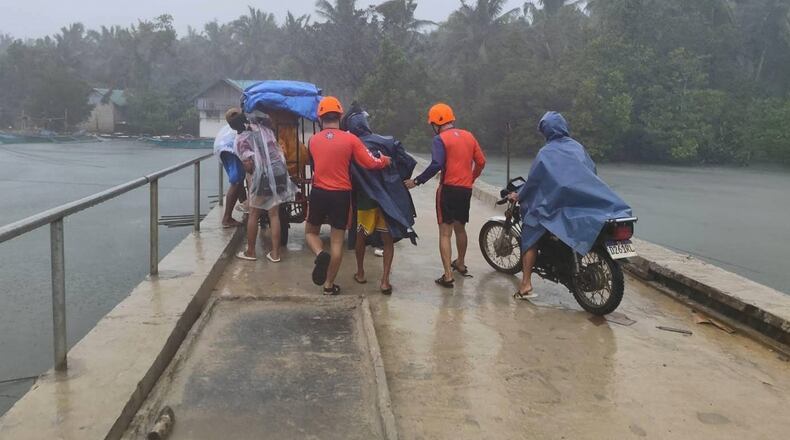 In this photo provided by the Philippine Coast Guard, rescuers evacuate people to safer grounds in Quezon province, eastern Philippines as Typhoon Fung-wong enters the country on Sunday Nov. 9 2025. (Philippine Coast Guard via AP)