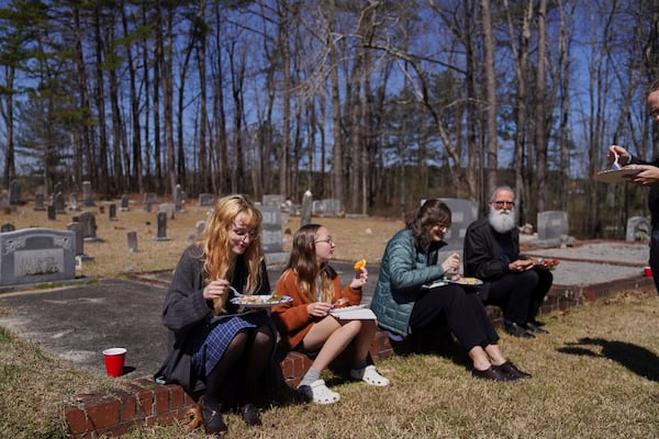 Sacred Harp singers sit among the headstones at Holly Springs Primitive Baptist Church for a midday potluck in Bremen, Ga., on Saturday, March 22, 2025. (AP Photo/Jessie Wardarski)