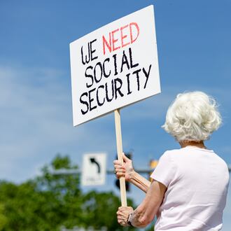 Lynn McKerral holds a sign supporting Social Security Administration workers on Security Boulevard in front of the agency's headquarters in Woodlawn, Md., on Tuesday, May 20, 2025. (Wesley Lapointe for The Washington Post via Getty Images)