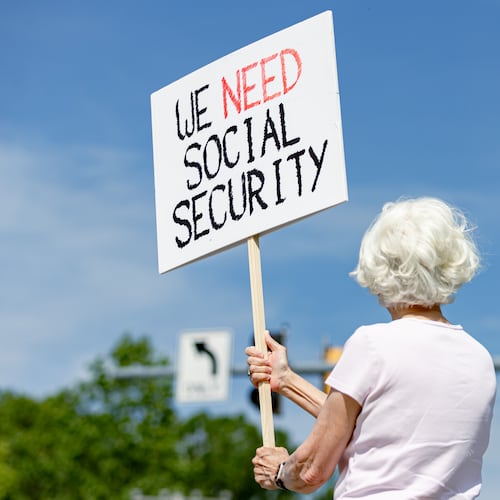 Lynn McKerral holds a sign supporting Social Security Administration workers on Security Boulevard in front of the agency's headquarters in Woodlawn, Md., on Tuesday, May 20, 2025. (Wesley Lapointe for The Washington Post via Getty Images)