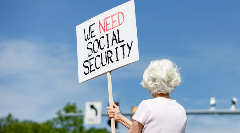 Lynn McKerral holds a sign supporting Social Security Administration workers on Security Boulevard in front of the agency's headquarters in Woodlawn, Md., on Tuesday, May 20, 2025. (Wesley Lapointe for The Washington Post via Getty Images)