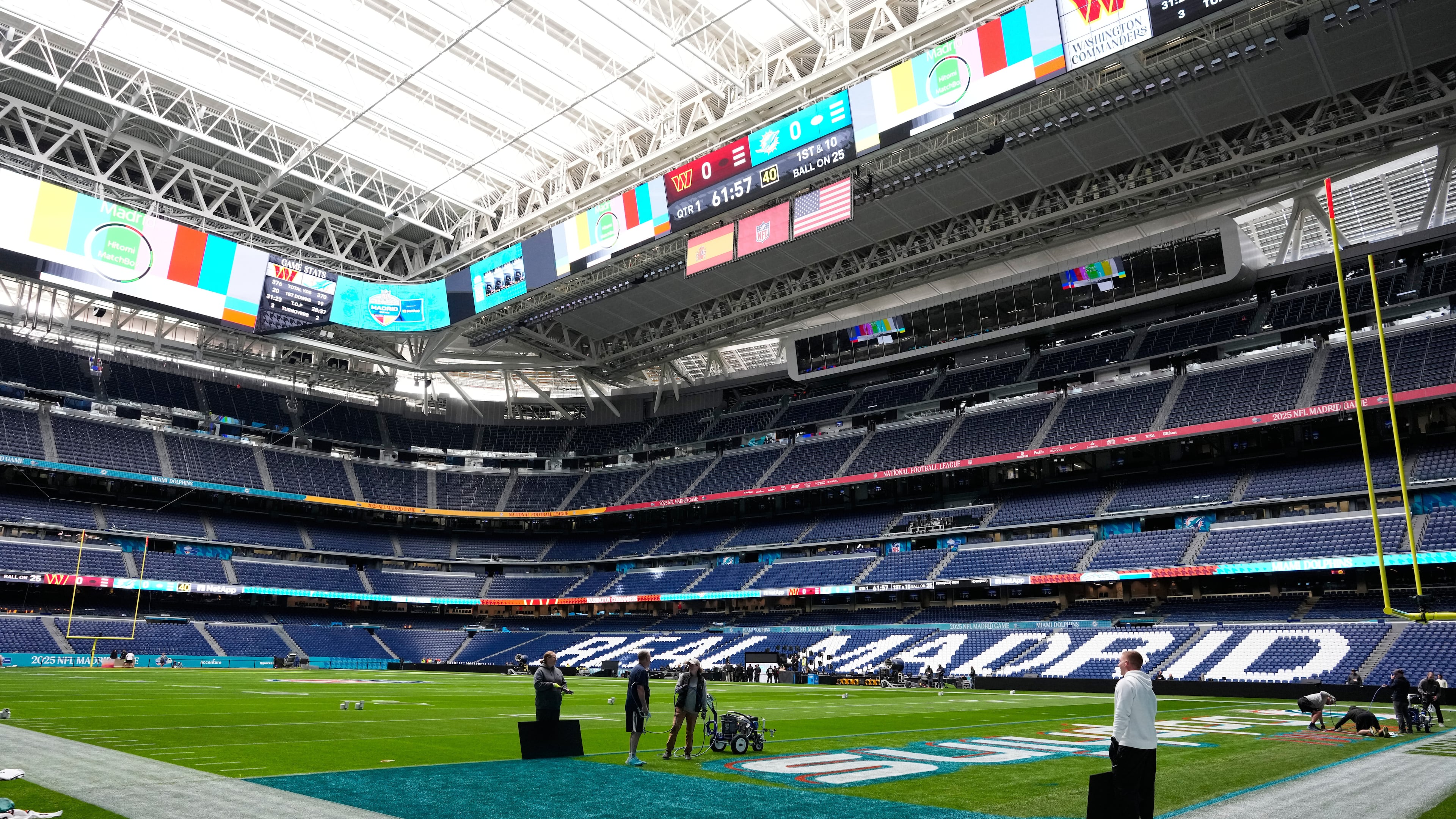 Workers prepare the field at the Santiago Bernabeu stadium ahead of an NFL game between the Miami Dolphins and Washington Commanders in Madrid, Spain, Friday, Nov. 14, 2025. (AP Photo/Steve Luciano)