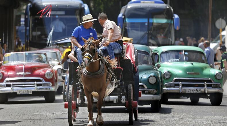Tourist buses share the road along with vintage American cars and a horse drawn buggy in Havana, Cuba. (Al Diaz/Miami Herald/TNS)