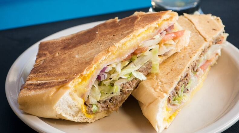 Rey’s Cuban sandwich with roast pork marinated with Papi’s secret recipe, ham, Swiss cheese, dill pickles, mustard and mayonnaise on Cuban bread, served here with a mojito. CONTRIBUTED BY MIA YAKEL