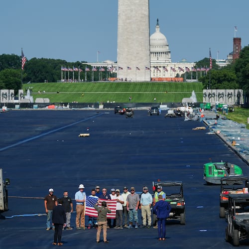 Interior Secretary Doug Burgum, center, poses for a photo with workers while touring the Lincoln Memorial Reflecting Pool after it was coated in a blue swimming pool surface ahead of the United States' 250th anniversary, Wednesday, June 3, 2026, in Washington. (AP Photo/Julia Demaree Nikhinson)