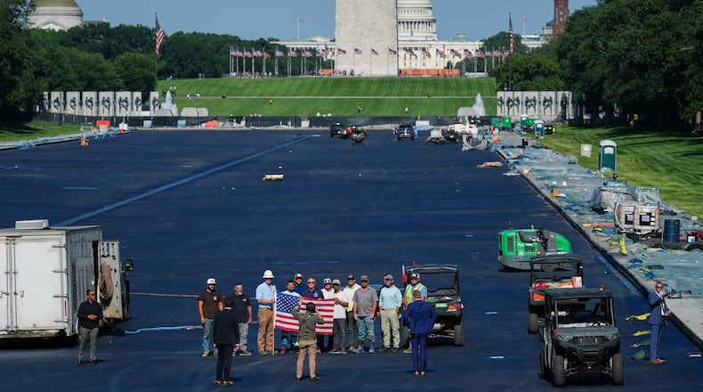 Interior Secretary Doug Burgum, center, poses for a photo with workers while touring the Lincoln Memorial Reflecting Pool after it was coated in a blue swimming pool surface ahead of the United States' 250th anniversary, Wednesday, June 3, 2026, in Washington. (AP Photo/Julia Demaree Nikhinson)