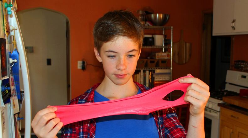 FILE - Astrid Rubens demonstrates the elasticity of homemade slime in her kitchen in St. Paul, Minn., June 21, 2017. (AP Photos/Jeff Baenen, File)