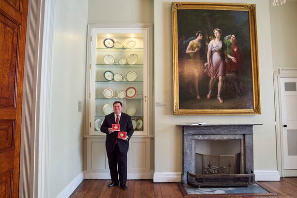 White House Historical Association President Stewart McLaurin poses with the 2025 White House Christmas ornament, seen both front and back, in front of a display of White House china, Thursday, April 10, 2025, at the association in Washington. (AP Photo/Jacquelyn Martin)