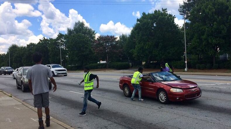 Young men sell water at the corner of Northside Drive and Joseph E. Boone Boulevard. Photo by Bill Torpy/AJC