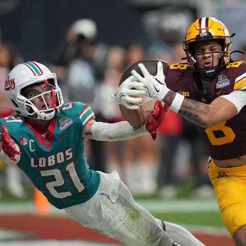 Minnesota defensive lineman Steven Curtis, right, scores a touchdown in overtime in front of New Mexico safety Austin Brawley (21) during a Rate Bowl NCAA college football game, Friday, Dec. 26, 2025, in Phoenix. (AP Photo/Rick Scuteri)
