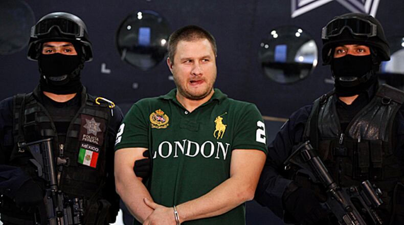 Federal police stand guard by Texas-born kingpin Edgar Valdez Villarreal, alias "the Barbie," during his presentation to the press in Mexico City, Tuesday Aug. 31, 2010. Valdez, who was captured on Monday by federal police, faces drug trafficking charges in the U.S. and has been blamed for a vicious turf war that has included bodies hung from bridges and shootouts in central Mexico.