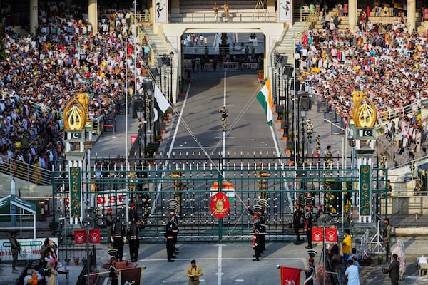 Pakistan's Rangers soldiers, in black, and Indian Border Security Forces soldiers, behind the gate, lower their flags during a daily closing ceremony at the Wagah, a joint post on the Pakistan and India border, near Lahore, Pakistan, Monday, May 5, 2025. (AP Photo/K.M. Chaudary)