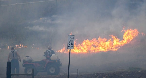 People watch as fire burns along Hatwai Road Saturday, May 31, 2025, in north Lewiston, Idaho. (August Frank/Lewiston Tribune via AP)
