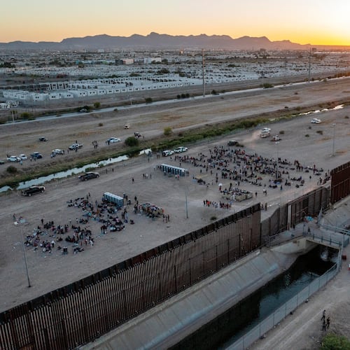 FILE - As the sun sets, migrants wait outside a gate in the border fence to enter into El Paso, Texas, to be processed by Border Patrol, May 11, 2023. (AP Photo/Andres Leighton, File)