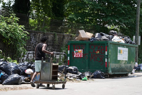 A man takes trash to a garbage collection site, Wednesday, July 9, 2025, in Philadelphia. (AP Photo/Matt Slocum)
