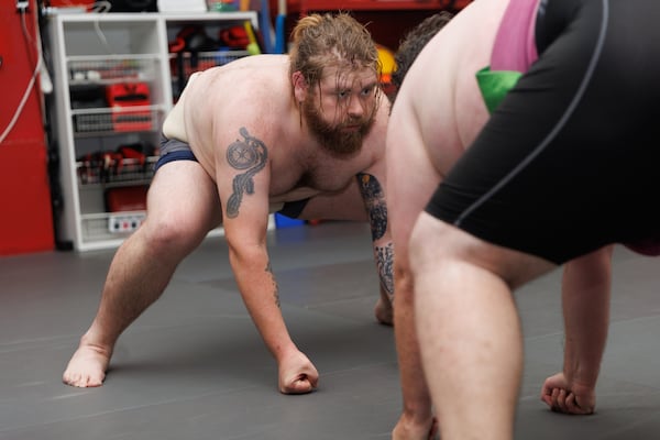 Lane Williams crouches and places his fists on the ground to complete the beginning stance during Black Dragon Beya sumo practice at Atlanta Kick in Atlanta, June 30, 2026. (Estela Muñoz/AJC)