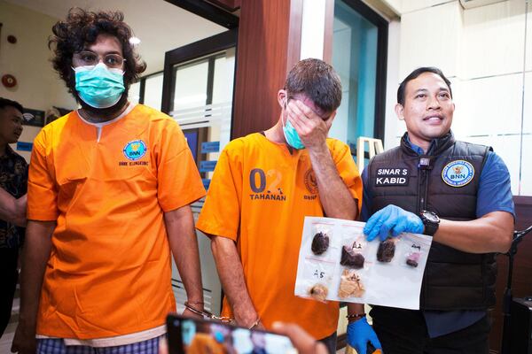 Australian national identified only as P.R., center, and an Indian national identified as H.V., left, who were arrested for drug possession, react as a National Narcotics Agency officer shows evidence confiscated from them, during a press conference in Denpasar, Bali, Indonesia Thursday, June 5, 2025. (AP Photo/Firdia Lisnawati)