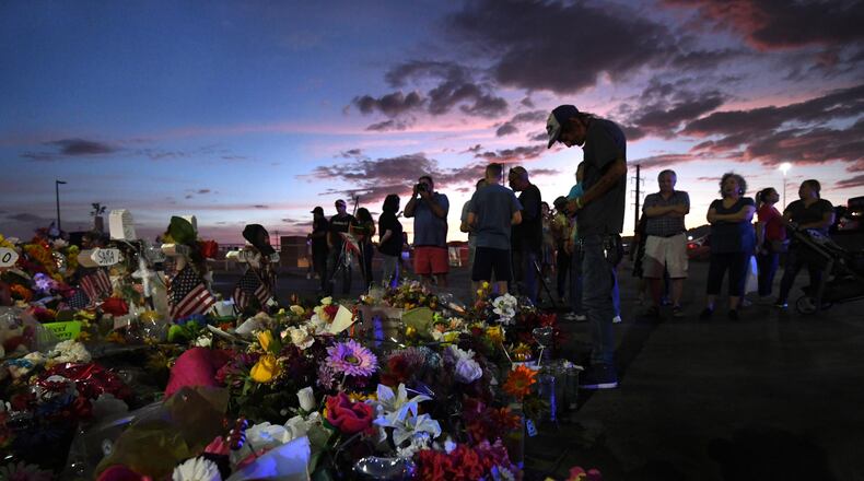 El Paso, Texas — Antonio Basco stands silently at his wife’s cross as family members visit the memorial site at dusk after funeral services that day for mass shooting victim Margie Reckard. (Carol Guzy/ZUMA Wire/TNS)