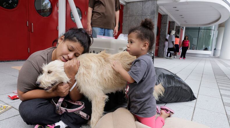 Tiffany Duron and her daughter Emma Sledge, 3, hug their dog Daisy on Aug. 30, 2017, outside the George R. Brown Convention Center where they took shelter after Hurricane Harvey flooded their home in Houston.