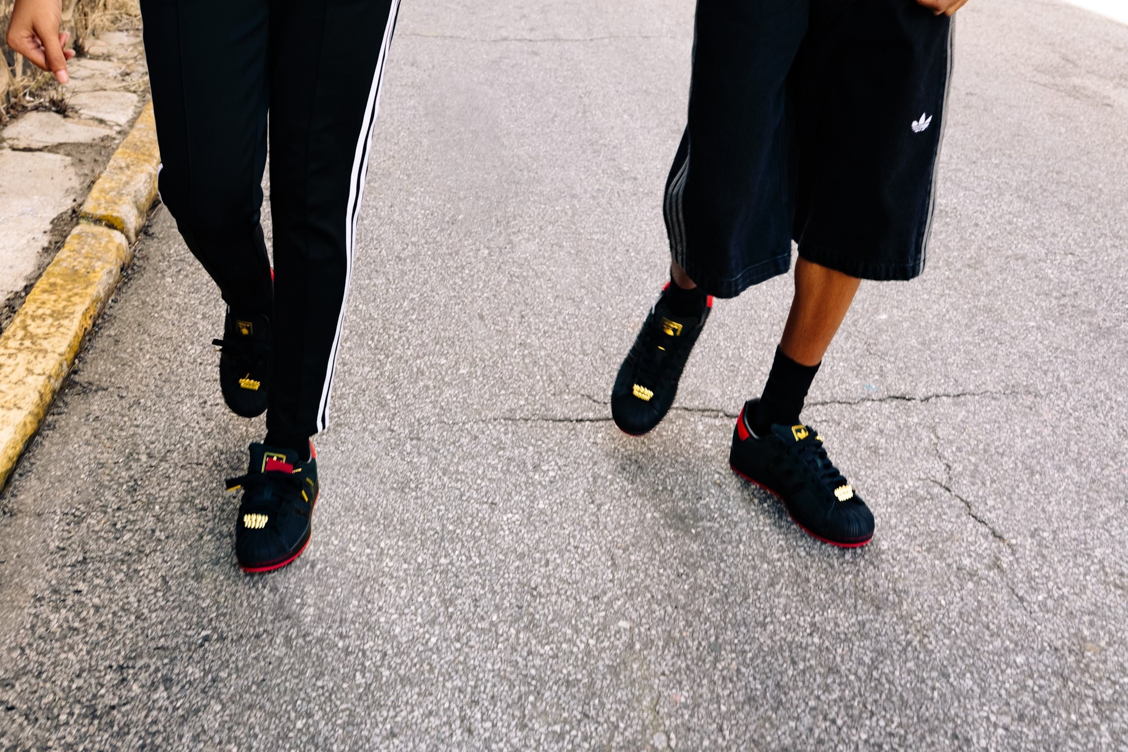 Two models wear the 2025 limited-edition "404 Day!" sneaker, created in collaboration with the 404 Collective, The Athlete's Foot and Adidas. A lace lock on the front of each shoe was created to resemble gold teeth.