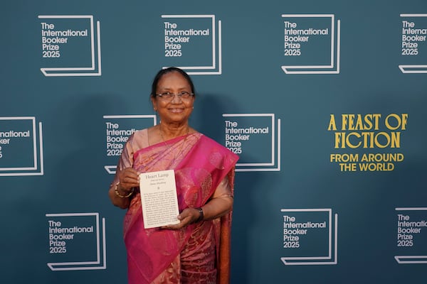 Banu Mushtaq, author of 'Heart Lamp' holds her book as she poses for photographers upon arrival for the International Booker Prize, in London, Tuesday, May 20, 2025.(AP Photo/Alberto Pezzali)