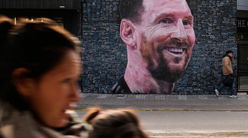 People walk past a mural of Lionel Messi by artist Leonel Garcia, which includes the names of local residents inscribed by them as a tribute to the soccer star, in Berazategui, on the outskirts of Buenos Aires, Argentina, Monday, June 22, 2026. (AP Photo/Gustavo Garello)