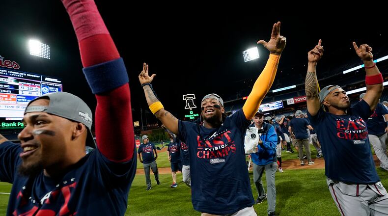 Atlanta Braves' Orlando Arcia, from left, Ronald Acuna Jr. and Eddie Rosario celebrate after clinching their sixth consecutive NL East title by defeating the Philadelphia Phillies in a baseball game, Wednesday, Sept. 13, 2023, in Philadelphia. (AP Photo/Matt Slocum)