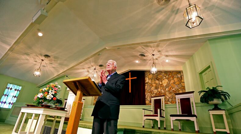 Jimmy Carter, the 39th President of the United States, reads some passages of scripture during his Sunday school lesson at Maranatha Baptist Church on Sunday, June 15, 2014, in Plains. He made the cross behind him, one of many woodworking projects he pursued. (Curtis Compton for the AJC 2014)