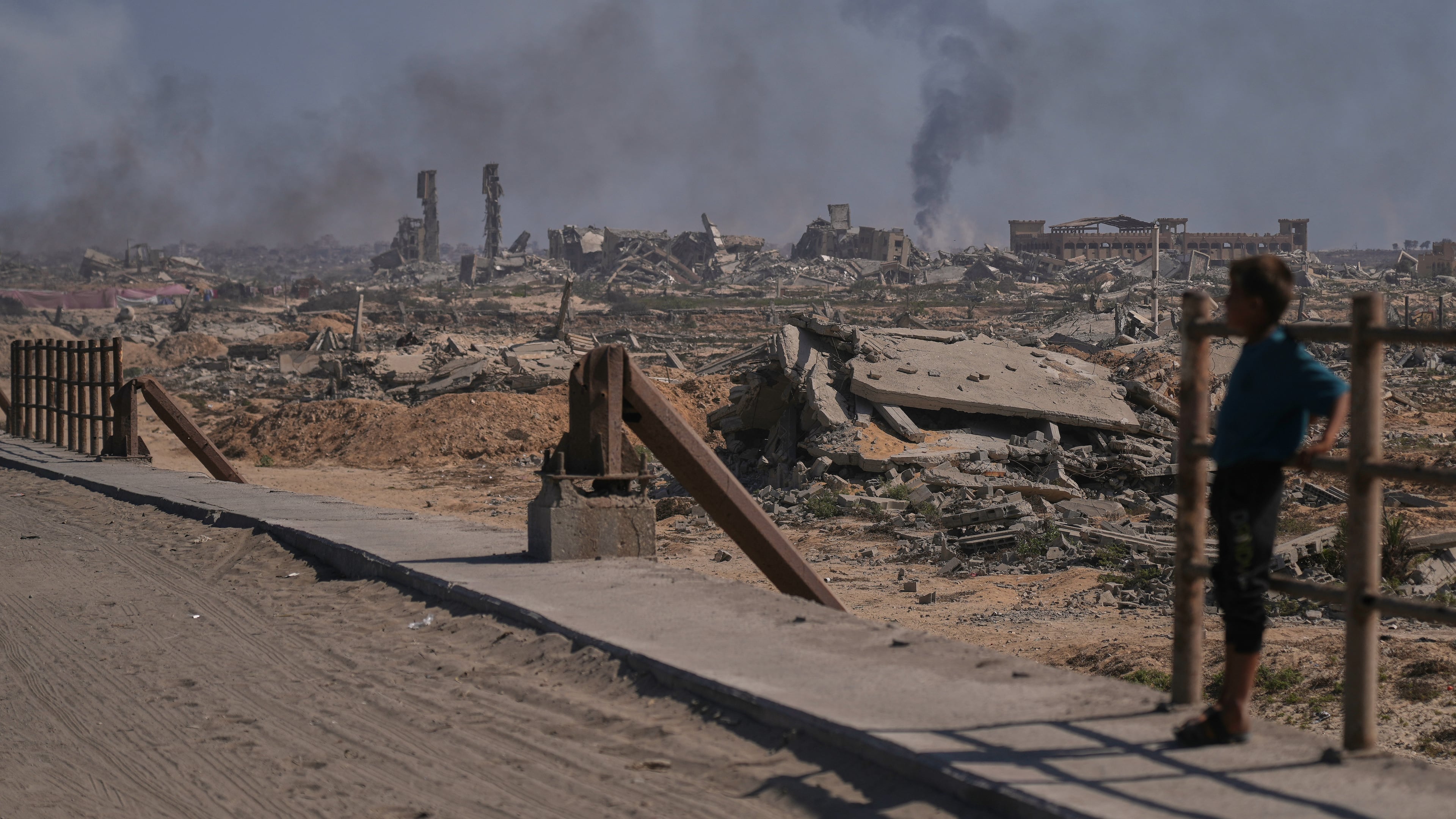 A displaced Palestinian boy looks at smoke rising into the sky following an Israeli military strike in Gaza City, as seen from the central Gaza Strip, Thursday, Oct. 2, 2025. (AP Photo/Abdel Kareem Hana)