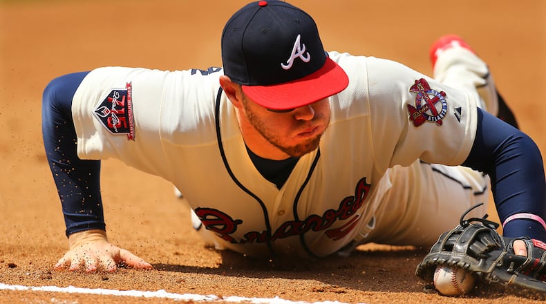 DIVING SAVE--042714 ATLANTA: Braves first baseman Freddie Freeman makes a diving play on the ball just shy of the foul line and beats out Reds batter Billy Hamilton to first base for the out during the 6th inning of their MLB baseball game on Sunday, April 27, 2014, in Atlanta. CURTIS COMPTON / CCOMPTON@AJC.COM