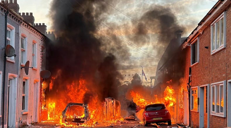 Vehicles set on fire by protesters burn on Lendrick Street in east Belfast, Northern Ireland, on Tuesday, June 9, 2026, after the arrest of a Sudanese man accused of stabbing a man in the northern part of the city. (PA via AP)