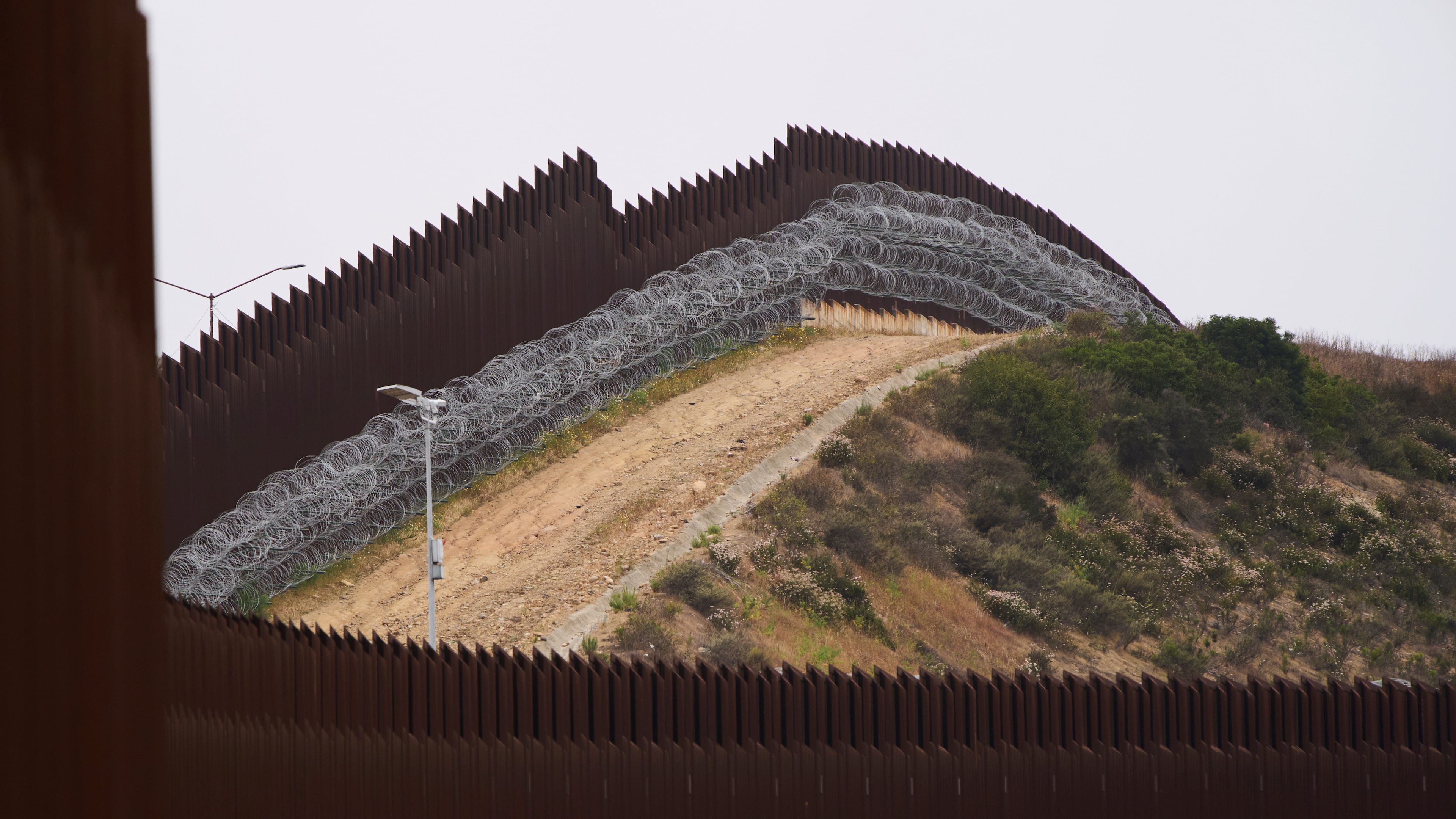 FILE - Concertina wire lines the interior of a border wall separating Tijuana, Mexico, from the United States, June 4, 2025, in San Diego. (AP Photo/Gregory Bull, File)