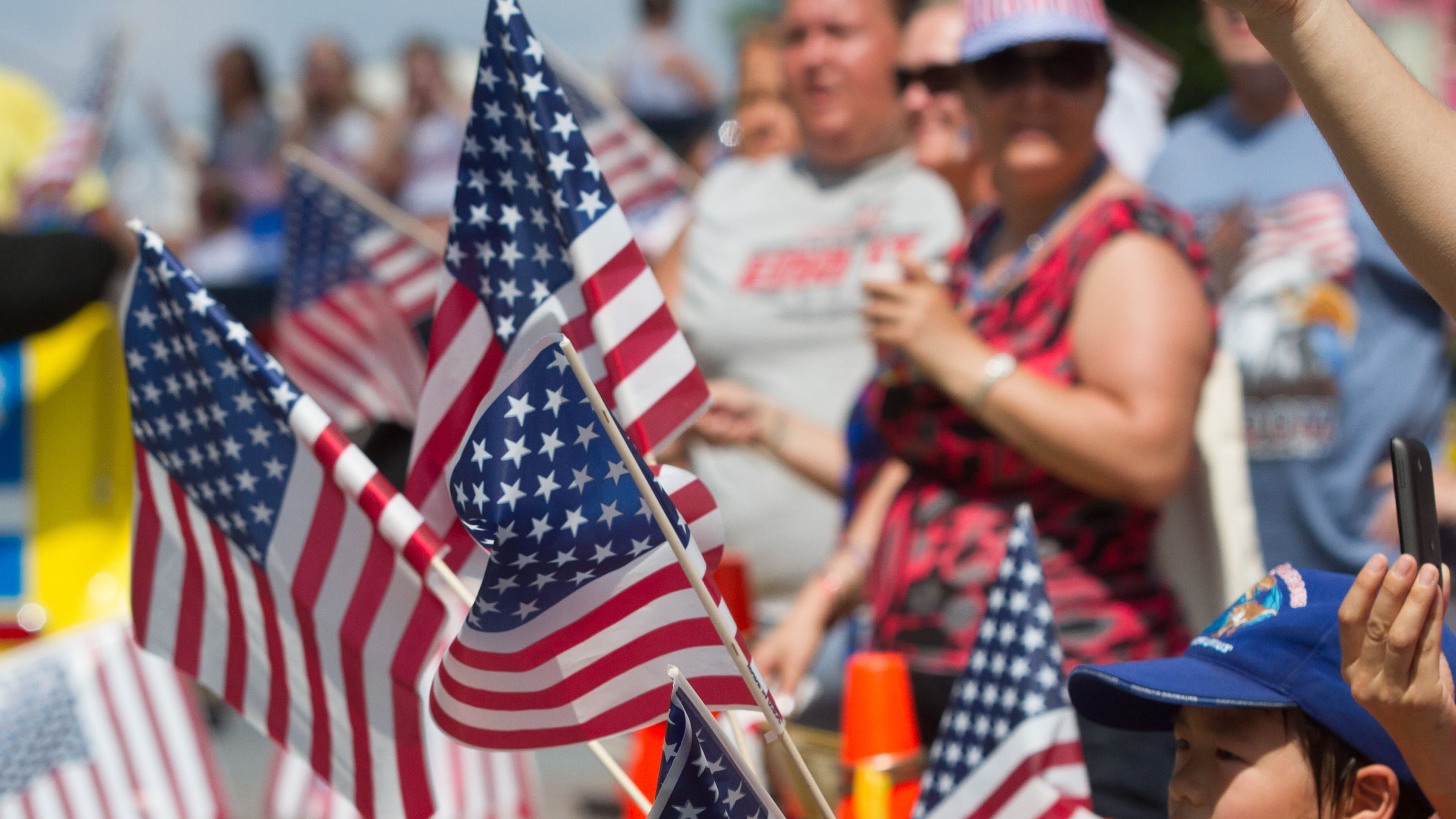 Katsuhiro Watanabe waves four American flags as the Marietta Freedom Parade makes its way down Roswell Street on Tuesday, July 4, 2016, in Marietta, Ga. (Steve Schaefer for the AJC)