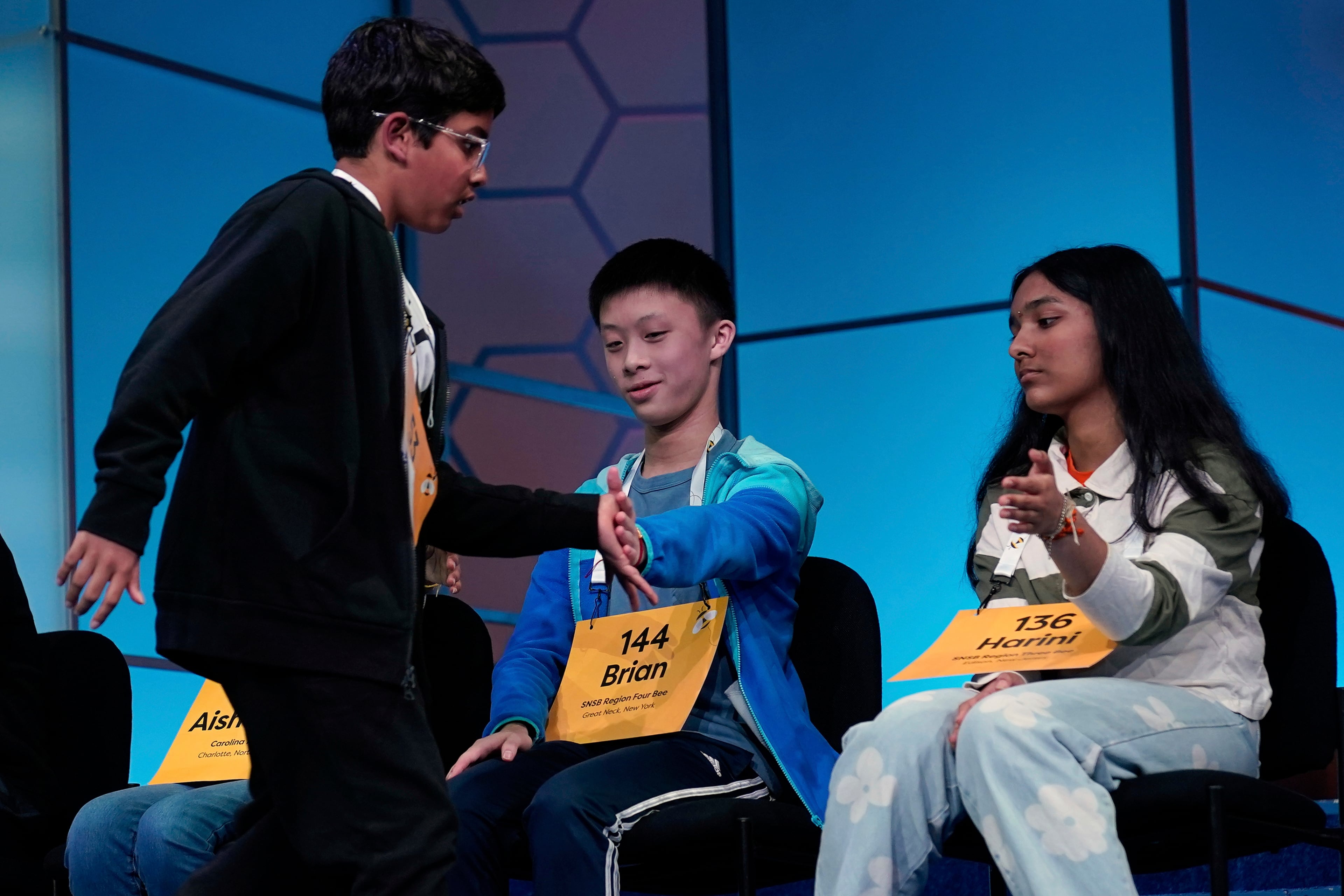 Harini Murali, 13, of Edison, N.J., and Brian Liu, 13, of Great Neck, N.Y., congratulate Sarv Dharavane, 11, of Tucker, Ga., after he spelled his word correctly iin the finals of the Scripps National Spelling Bee at the Gaylord National Resort & Convention Center Thursday, May 29, 2025, in Oxon Hill, Md. (AP Photo/Jose Luis Magana)