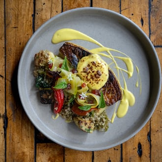A squash entree plated with dramatic sweeps of sauce, shown on a wooden table.