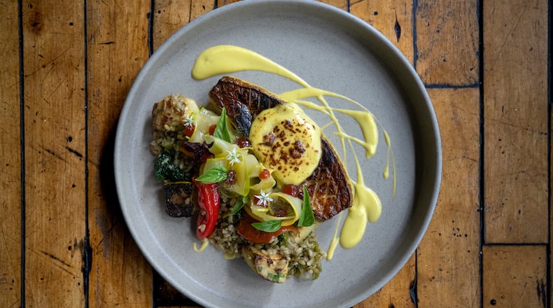 A squash entree plated with dramatic sweeps of sauce, shown on a wooden table.