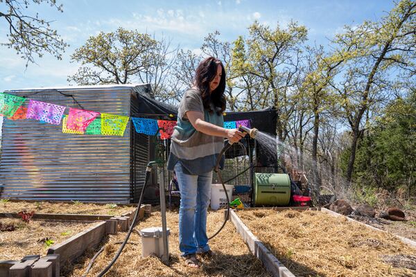 Erika Wright, a mother whose two school-age children attend a rural school district in Cleveland County waters her garden at her home in Noble, Okla., on Tuesday, April 15, 2025. (AP Photo/Nick Oxford)