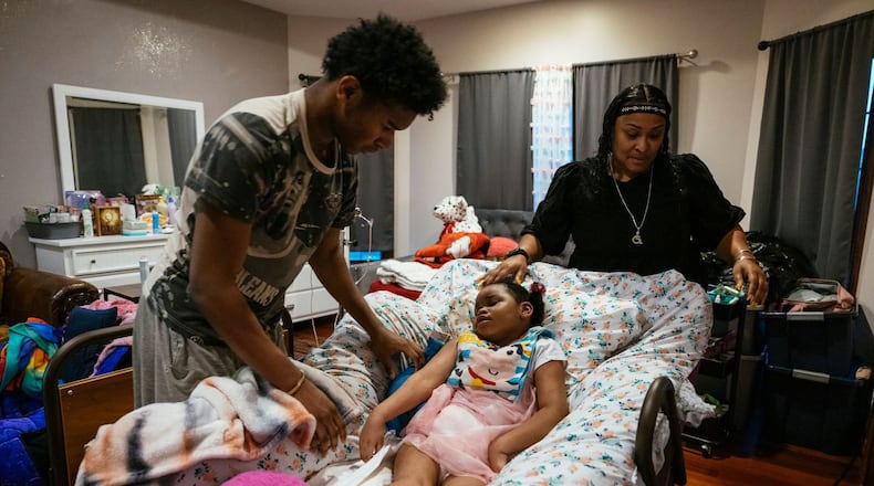 Tyrus Hike (left) helps his mother, Rhonda Jones, administer ibuprofen to Alayna at their home in Crown Point, Indiana. Alayna was injured during her birth and has cerebral palsy. She was recently hospitalized with respiratory syncytial virus, or RSV. (Taylor Glascock for KHN)