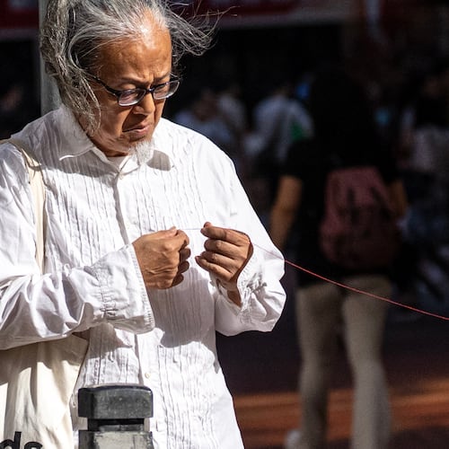 Artist Sanmu Chen displays a red thread as he performs on the street in the Causeway Bay area on the eve of the 37th anniversary of China's Tiananmen Square crackdown in Hong Kong, Wednesday, June 3, 2026. (AP Photo/Chan Long Hei)