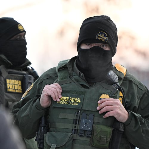 FILE - Federal agents look on as protesters gather outside the Bishop Henry Whipple Federal Building, Thursday, Jan. 8, 2026, in Minneapolis, Minn. (AP Photo/Tom Baker, File)