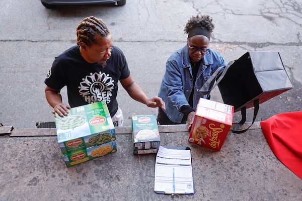 Hosea Helps volunteer Elger Fox (left) assists Yvette Johnsonas as she donates food on Friday, Nov. 7, 2025. Families are turning to food banks and pop-up pantries to get by. (Natrice Miller/AJC)